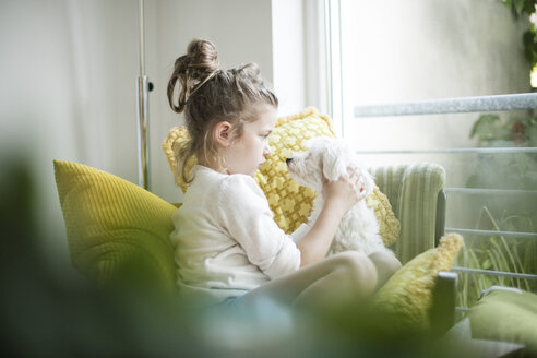 Kleines Mädchen sitzt mit ihrem Hund auf einem Sessel - MOEF00056