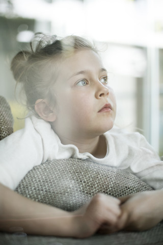 Porträt eines ernsten kleinen Mädchens, das aus dem Fenster schaut, lizenzfreies Stockfoto