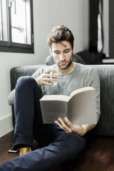 Young man reading book at home - GIOF02897