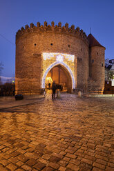 Poland, Warsaw, Old Town, cobbled street and Barbican fortification at night - ABOF00199