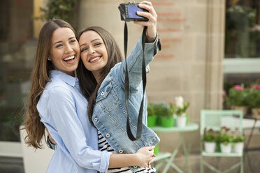 Laughing girlfriends taking a selfie in the street - CHAF01891