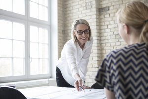 Mature businesswoman working with younger colleague in office - RBF05797