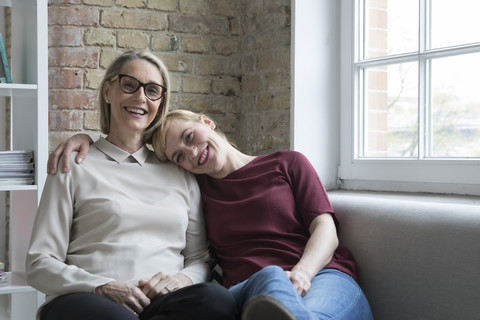 Mutter und Tochter sitzen auf der Couch und verbringen Zeit miteinander, lizenzfreies Stockfoto