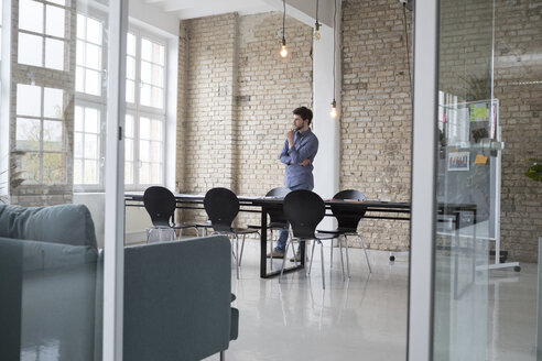 Junger Unternehmer, der in seinem Büro steht und denkt - RBF05806