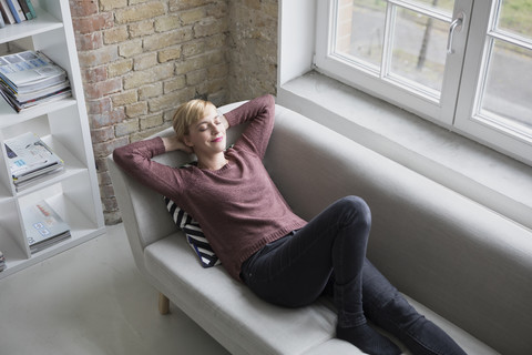 Frau entspannt sich auf der Couch zu Hause, lizenzfreies Stockfoto