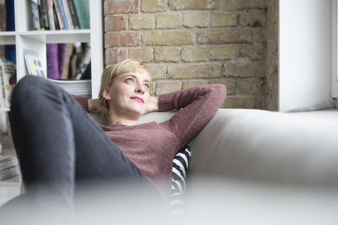 Frau entspannt sich auf der Couch zu Hause, lizenzfreies Stockfoto