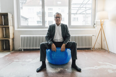 Senior businessman sitting on fitness ball - GUSF00001