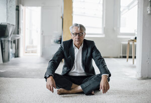 Älterer Geschäftsmann sitzt auf dem Boden und meditiert - GUSF00009
