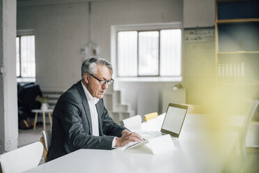 Senior businessman using tablet at table - GUSF00035