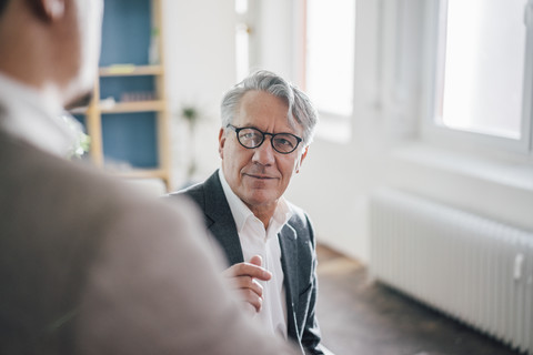 Älterer Geschäftsmann mit Partner im Büro, lizenzfreies Stockfoto