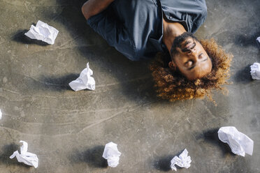 Mann auf dem Boden liegend, umgeben von zerknittertem Papier - KNSF01707
