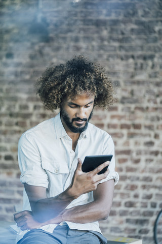 Junger Mann überprüft sein Tablet, lizenzfreies Stockfoto