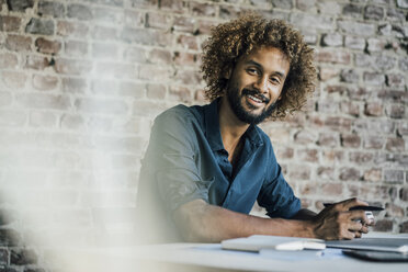 Portrait of smiling young man at desk - KNSF01713