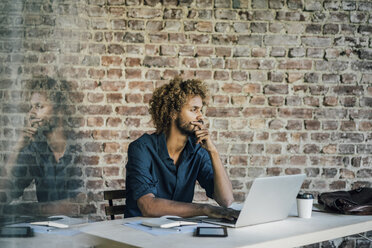 Young man at desk thinking - KNSF01715