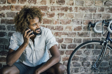 Smiling young man with bicycle on cell phone - KNSF01719
