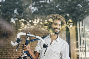 Lächelnder junger Mann mit Fahrrad - KNSF01726