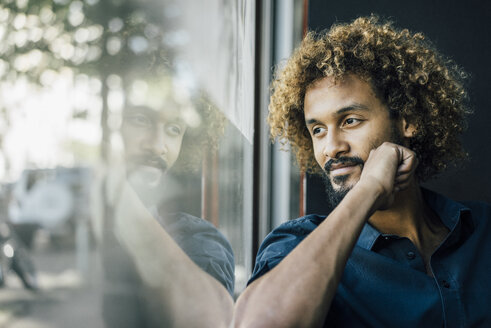 Man with beard and curly hair looking out of window - KNSF01727