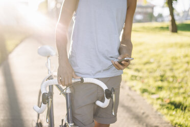 Close-up of man with bicycle checking cell phone - KNSF01728