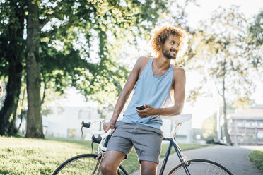 Mann mit Bart und lockigem Haar mit Fahrrad im Park - KNSF01730