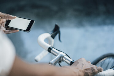 Nahaufnahme eines Mannes mit Fahrrad, der sein Mobiltelefon überprüft - KNSF01745
