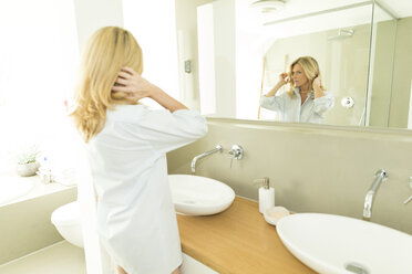 Frau betrachtet ihr Spiegelbild im Badezimmer - MAEF12246