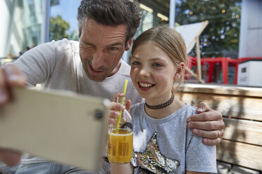 Verspielter Vater und Tochter machen ein Selfie in einem Straßencafé - SUF00212