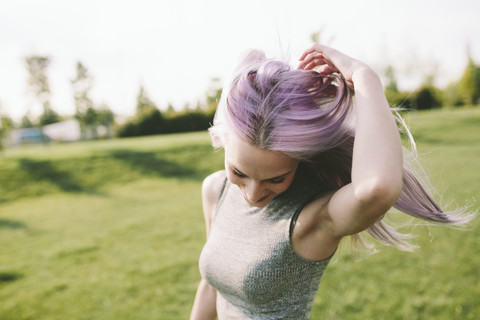 Junge Frau mit rosa grauen Haaren tanzt auf einer Wiese, lizenzfreies Stockfoto