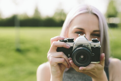 Junge Frau fotografiert mit Kamera in der Natur - GIOF02902