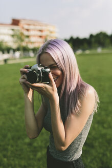 Junge Frau fotografiert mit Kamera in der Natur - GIOF02904