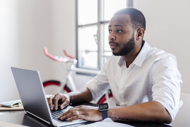 Man using laptop at desk in home office - GIOF02913