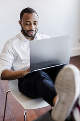 Mann mit Laptop im Heimbüro mit Füßen auf dem Schreibtisch - GIOF02923