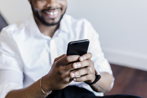 Nahaufnahme eines lächelnden Mannes, der ein Mobiltelefon benutzt, lizenzfreies Stockfoto