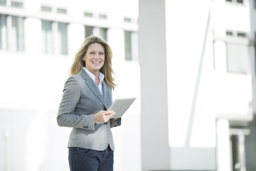 Happy businesswoman holding tablet outdoors - MAEF12271