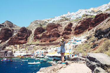 Griechenland, Santorini, Oia, Frau genießt die Aussicht im Fischerhafen mit dem weißen Dorf oberhalb der Klippe - GEMF01722