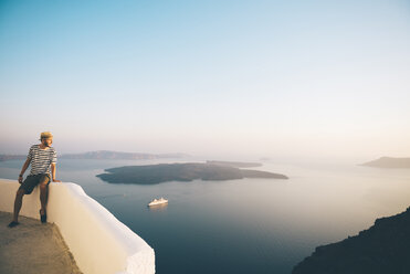 Griechenland, Santorin, Fira, Mann im Urlaub genießt den Sonnenuntergang über dem Meer - GEMF01736