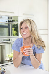 Happy woman at home with cup of coffee - MAEF12283