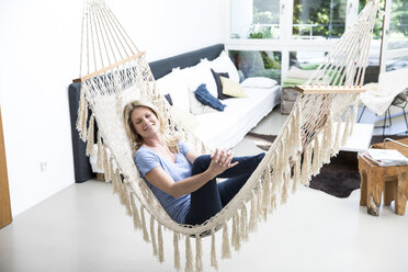 Relaxed woman at home lying in hammock - MAEF12296