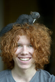 Porträt eines fröhlichen rothaarigen Teenagers mit Eichhörnchen auf dem Kopf - LBF01612