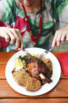 Nahaufnahme einer Frau, die in einem Straßenrestaurant Schweinshaxe isst - RTBF00988