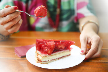 Nahaufnahme einer Frau, die in einem Straßencafé Erdbeerkuchen isst - RTBF00990