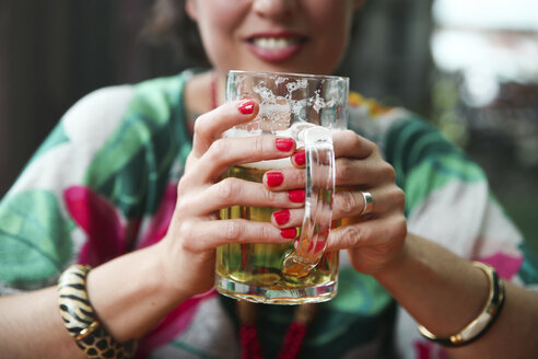 Close-up of woman holding a beer mug in a street restaurant - RTBF00992