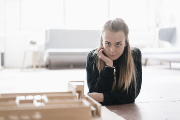 Porträt einer blonden jungen Frau mit Architekturmodell auf einem Tisch - GUSF00044