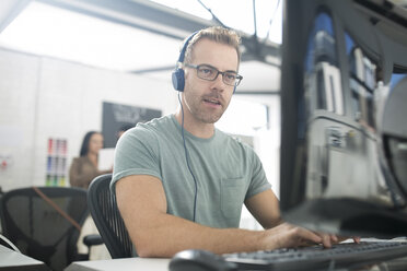 Employee wearing headphones at desk - ZEF14072