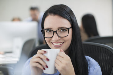 Mitarbeiterin genießt eine Tasse Kaffee an ihrem Schreibtisch - ZEF14075