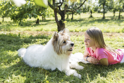 Mädchen liegend mit Hund auf Wiese - SHKF00764