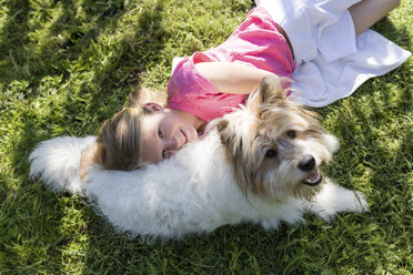 Girl lying with dog on meadow - SHKF00766