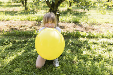 Girl inflating balloon on meadow - SHKF00773