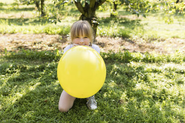 Mädchen bläst Luftballon auf Wiese auf - SHKF00773