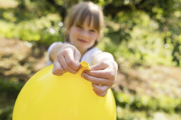 Mädchen hält Luftballon auf Wiese - SHKF00774