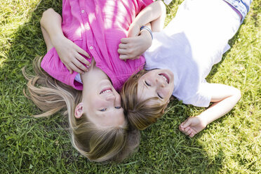 Two happy sisters lying in meadow - SHKF00777